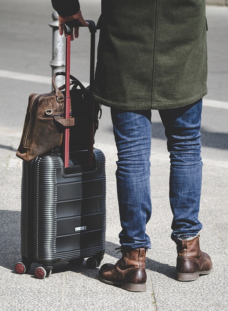 Man with jeans standing next to black suitcase