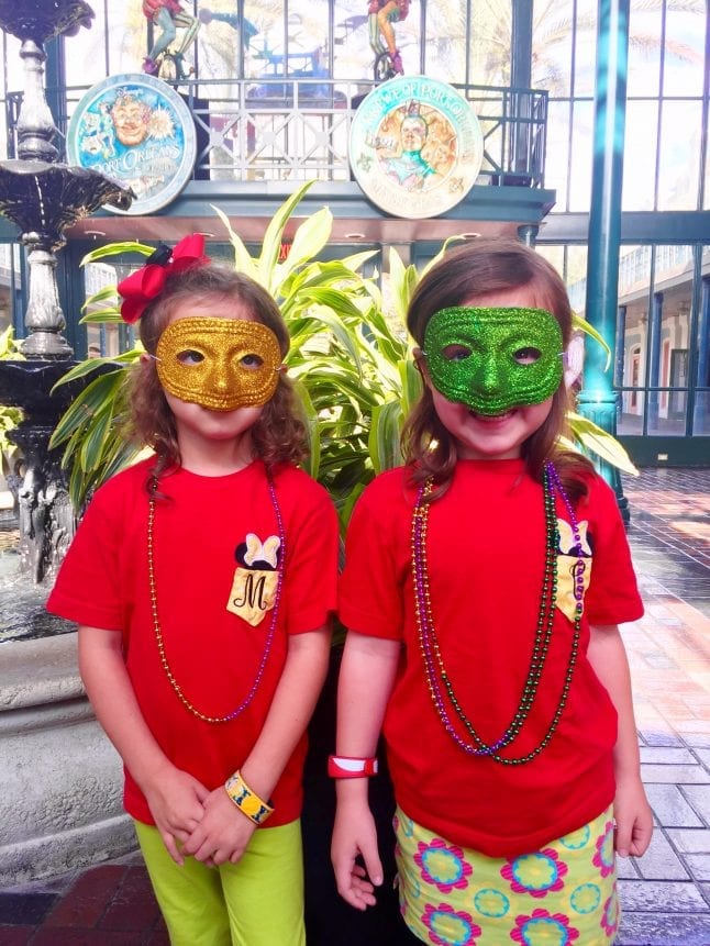 Two girls in red shirts and Mardi Gras masks
