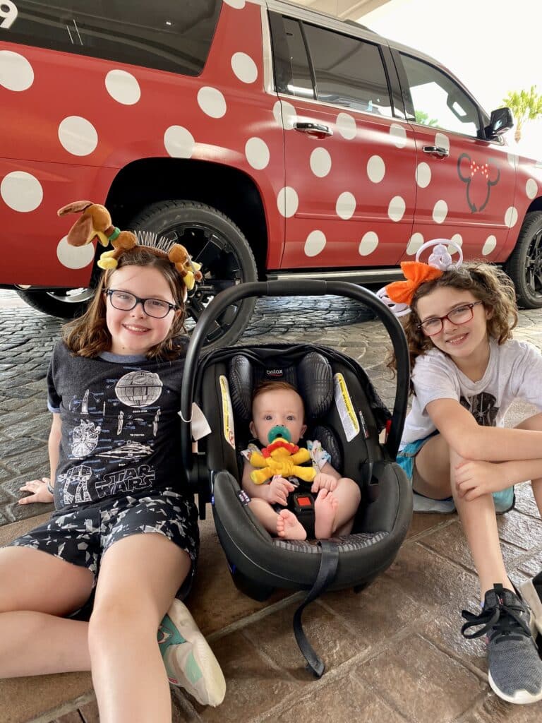 3 kids waiting to ride in a Minnie Van at Disney World
