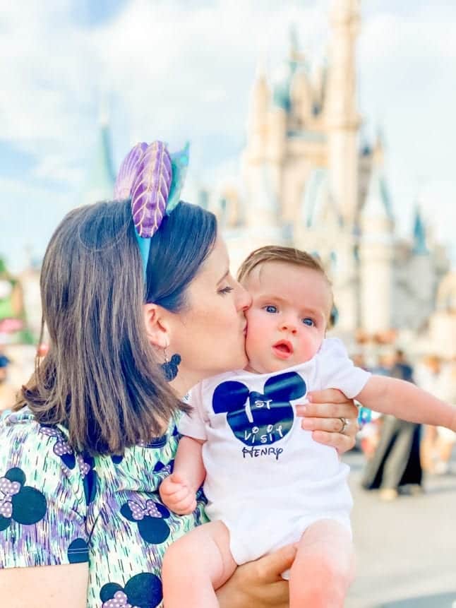 Mom kissing baby in front of Cinderella Castle